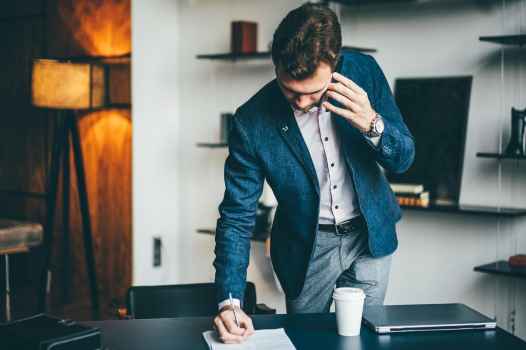 Serious manager making business call focused on document at workplace