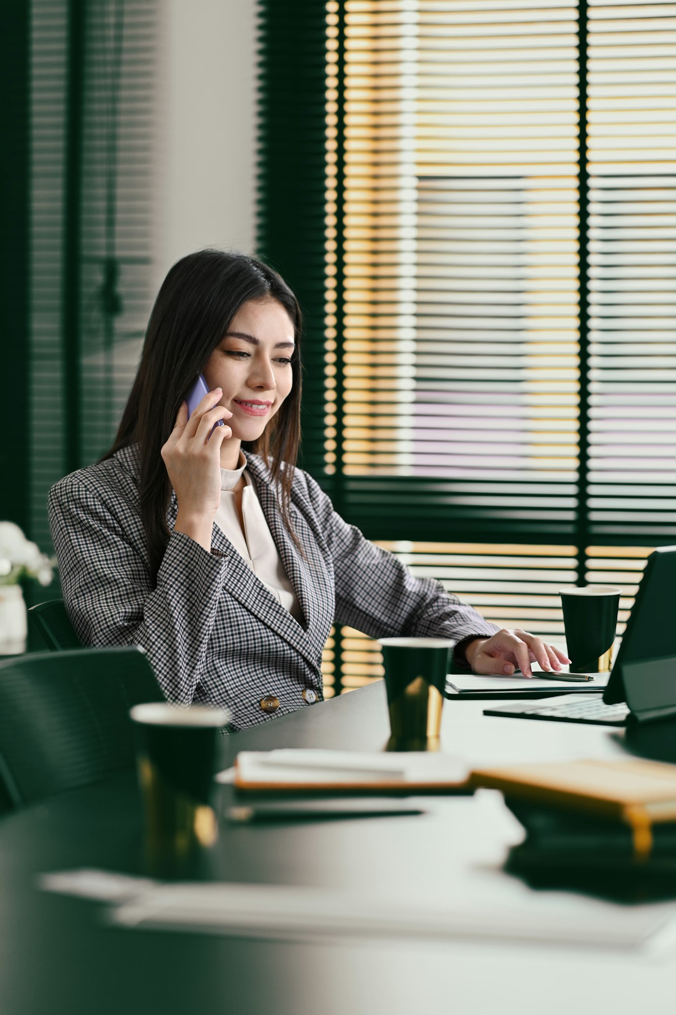 Successful businesswoman using laptop and talking on mobile phone with her business partner.